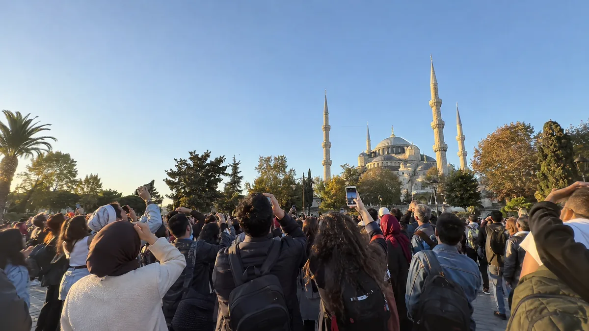A crowd looks up in a city square.